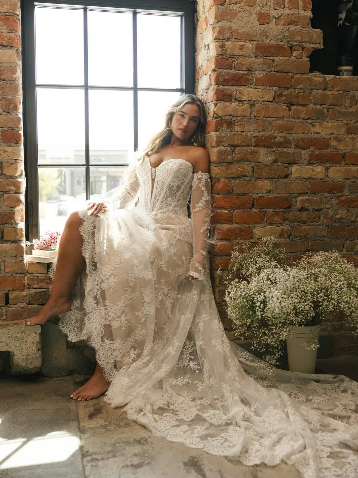 Bride seated in a lace long-sleeve gown by a window