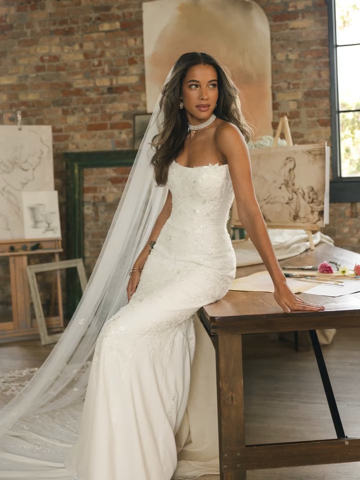 Bride seated on a table in an embellished fitted gown
