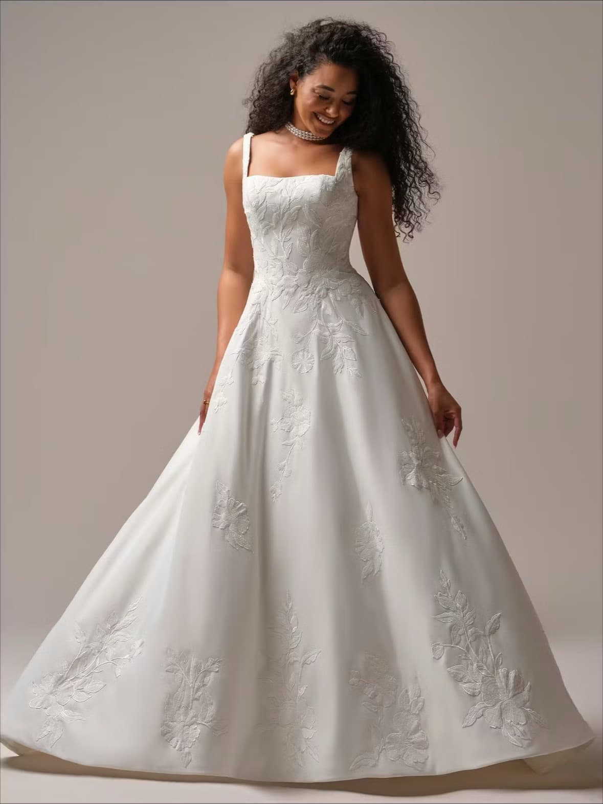 Bride in an appliqued ballgown smiling in studio